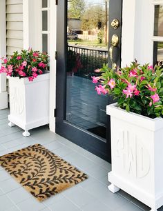 two white planters with pink flowers on the front porch