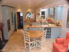 a kitchen with a table and chairs in the middle of it, surrounded by blue cabinets