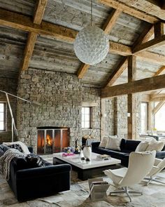 a living room filled with furniture and a fire place next to a stone wall covered in logs