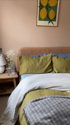 a bed with green and blue comforter next to a painting hanging on the wall