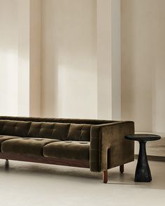 a brown couch sitting next to a table on top of a hard wood floor covered in white walls