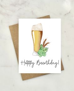 a happy birthday card with a glass of beer and hops on the table next to it