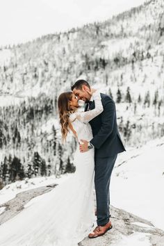 a bride and groom standing on top of a snow covered mountain in their wedding attire