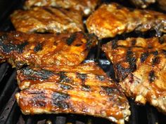 several pieces of meat cooking on a grill