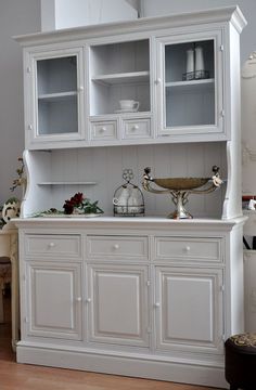 a white china cabinet with glass doors and drawers