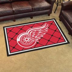 the detroit red wings rug is on the floor next to two brown leather couches