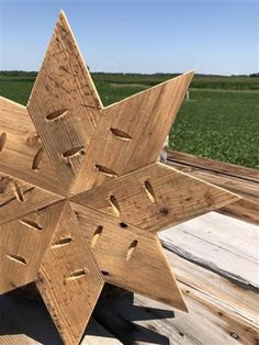 a wooden snowflake sitting on top of a wooden deck next to a field