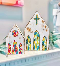 two painted wooden houses sitting on top of a mantle