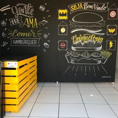 two chalkboard menus on the side of a building with yellow crates next to them