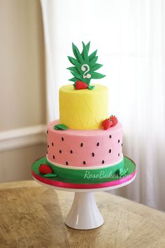 a three tiered cake with pineapple and strawberry on top