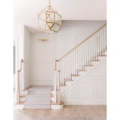 an empty room with stairs and a chandelier hanging from the ceiling above it