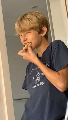 a young boy eating a doughnut while standing in front of a door