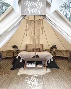 the inside of a tent that has a bed and pillows in it with white curtains