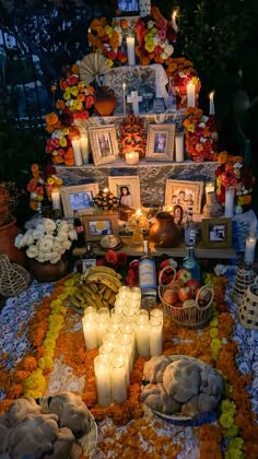 a table topped with candles and pictures covered in flowers next to other items on the ground