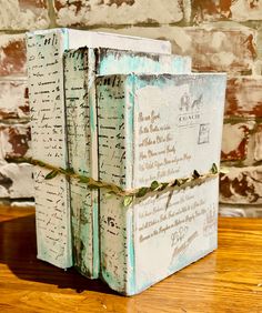 three books stacked on top of each other in front of a brick wall and wooden table