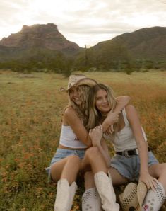 two young women sitting on the ground with their arms around each other