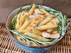 a bowl filled with pasta and chicken sitting on top of a wicker place mat