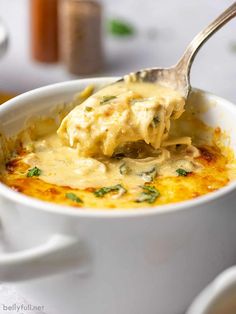 a spoon with some food in it on top of a white cup and saucer