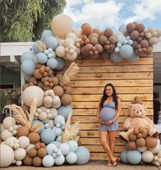 a pregnant woman standing in front of a backdrop made out of balloons and teddy bears