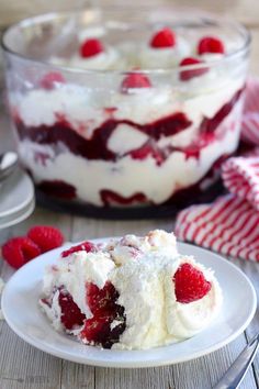 a white plate topped with a dessert covered in whipped cream and raspberries