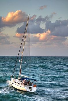 a sailboat sailing in the ocean under a cloudy sky