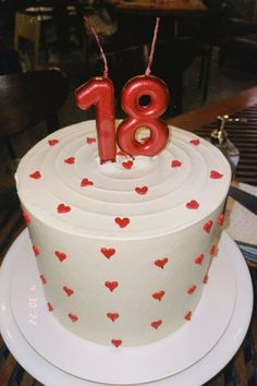 a white cake with red hearts and the number eighteen on top is sitting on a plate