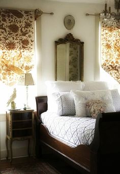 a bed sitting in a bedroom next to a window with curtains on top of it