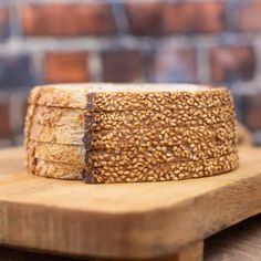 a piece of bread sitting on top of a cutting board next to a brick wall