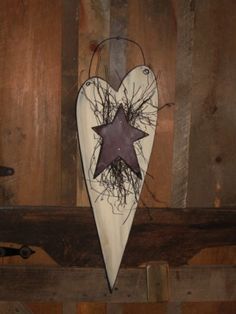 a wooden heart with a star hanging from it's side on a wood wall