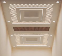 an empty room with white walls and wooden ceiling tiles on the ceiling, along with several recessed lights