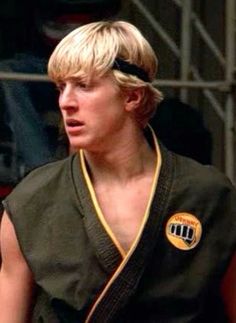 a young man with blond hair wearing a black belt