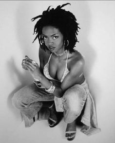 a black and white photo of a woman with dreadlocks sitting on the ground