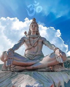 there is a large statue sitting on the ground in front of blue sky and clouds