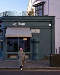 a person walking down the street in front of a building with a sign on it