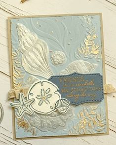 a close up of a card on a table with shells and seaweed in it