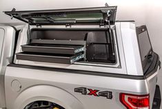 the back end of a silver truck with an open hatchback and storage compartment in it