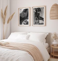 two paintings on the wall above a bed in a room with white sheets and pillows