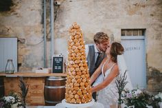 a bride and groom are standing in front of a tall cake that is made out of donuts