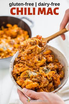 someone holding a spoon full of cheesy pasta in a bowl with the text gluten - free, dairy - free chili mac