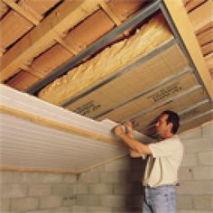 a man is working on the ceiling in his room with unfinished walls and wood beams