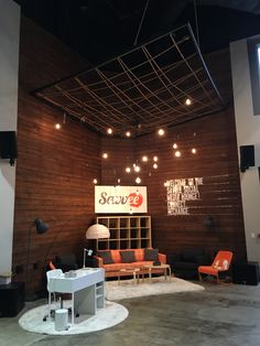 an empty room with couches, tables and chairs on the floor in front of a wooden wall