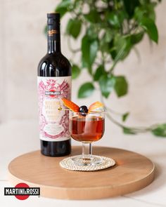 a bottle of wine sitting next to a glass with an orange slice in it on a wooden tray