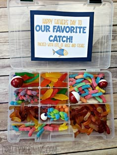 a plastic container filled with lots of colorful candies and marshmallows next to a sign that says happy father's day to our favorite catch