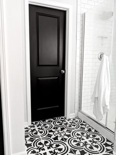 a bathroom with black and white tile flooring next to a shower door, towel rack and mirror