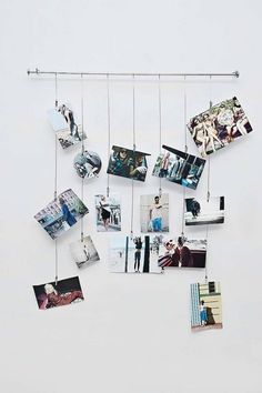 several pictures hanging from a metal bar on the wall with clothes pins attached to them