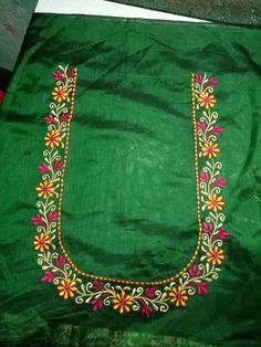 an embroidered green cloth with colorful flowers and beads on the border is sitting on a table