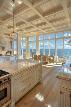 a large kitchen with an island, stove and dining room table overlooking the ocean is pictured in this image