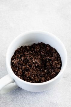 a white cup filled with dirt on top of a table