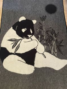 a black and white panda bear rug sitting on top of a wooden floor next to a potted plant