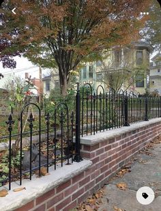 a fire hydrant sitting on the side of a brick wall next to a tree